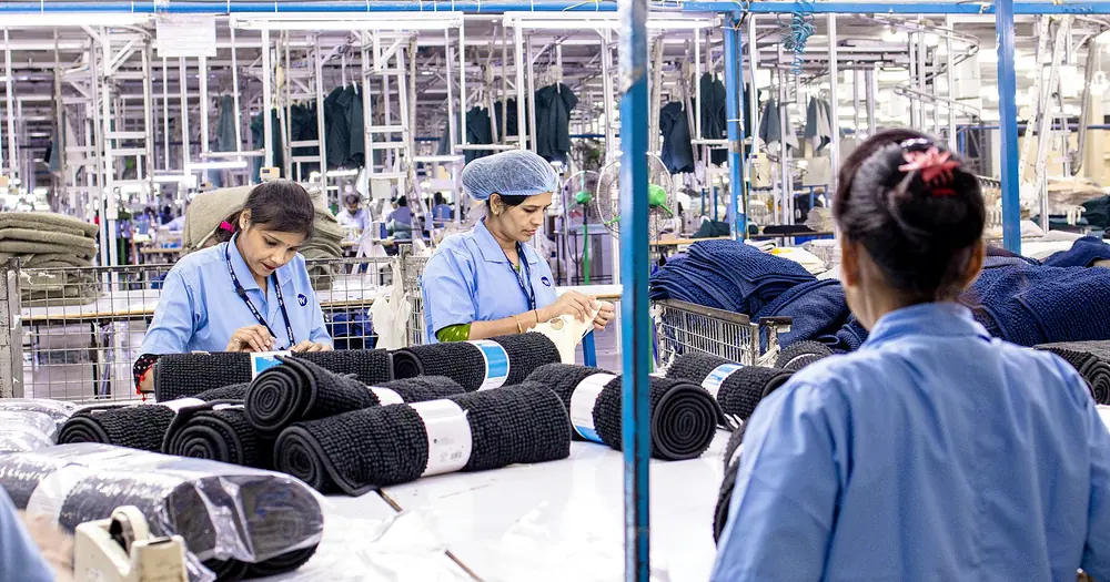 Equipe de funcionárias uniformizadas trabalhando lado a lado numa fábrica têxtil