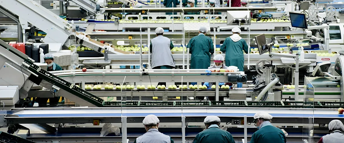 Equipe de funcionários uniformizados trabalhando em linha de produção
